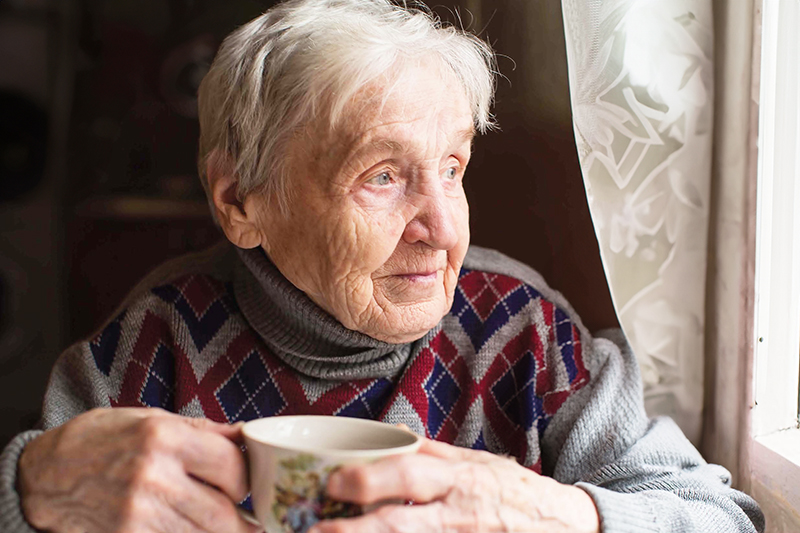 Long Term Care Reform - older woman with cup of coffee looking out a window