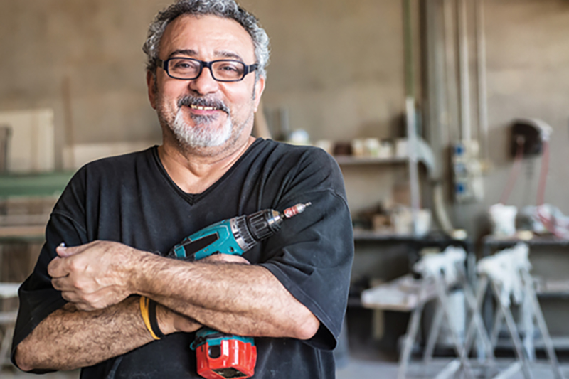 Older Workers - Man holding tools on construction site.